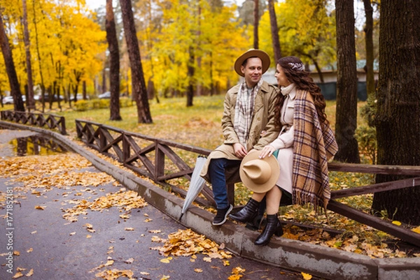 Obraz Charming couple enjoying a cozy moment outdoors in a city park during autumn. They share a joyful smile, conveying warmth and connection on a sunny day.
