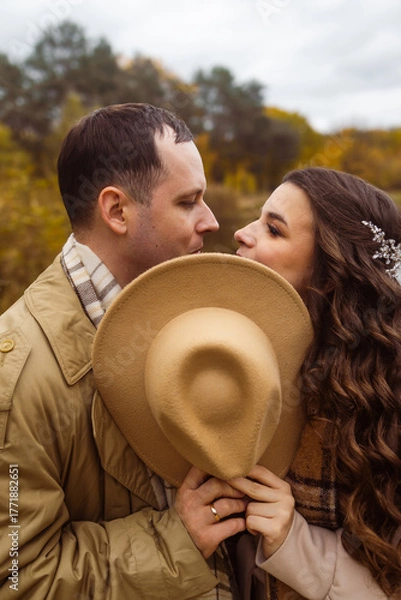 Obraz Charming couple enjoying a cozy moment outdoors in a city park during autumn. They share a joyful smile, conveying warmth and connection on a sunny day.