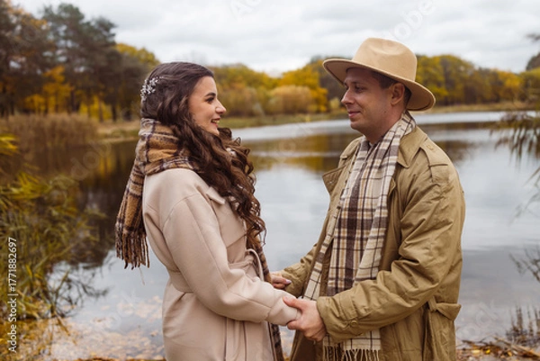 Obraz Charming couple enjoying a cozy moment outdoors in a city park during autumn. They share a joyful smile, conveying warmth and connection on a sunny day.