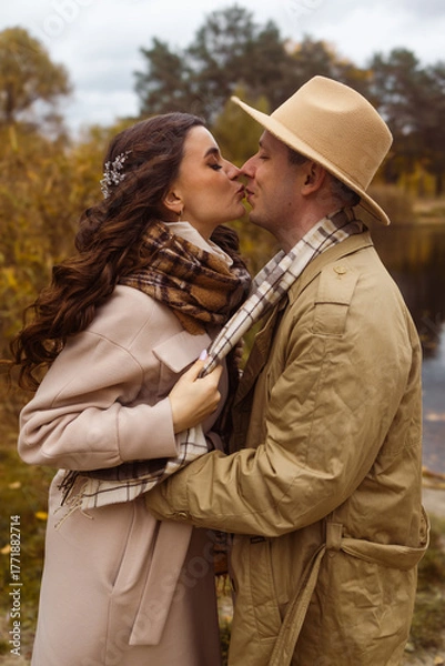 Obraz Charming couple enjoying a cozy moment outdoors in a city park during autumn. They share a joyful smile, conveying warmth and connection on a sunny day.