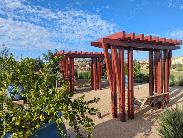 Fototapeta A pair of tandem swings under pergolas at a public park