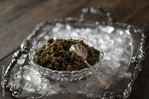 Fototapeta Black caviar and a spoon for caviar. The caviar is on ice. High-quality natural sturgeon black caviar close-up.