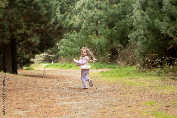 Fototapeta Joyful child running in nature's forest pathway. Nature