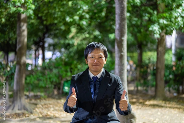 Fototapeta ベンチで親指を立てる笑顔のサラリーマン