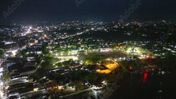 Fototapeta The atmosphere of Waingapu's Old Town to the Seaport seen from the air with a drone at night