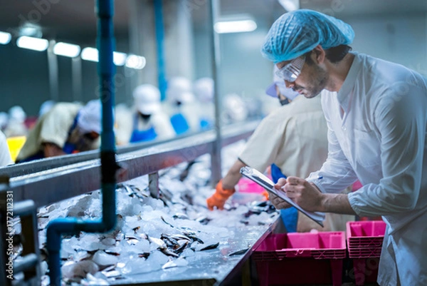 Fototapeta A Quality Assurance QA inspector audits a fish processing line for HACCP compliance. He is monitoring the smart factory's automated system and manual sorting.
