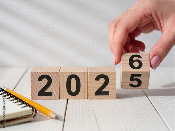 Fototapeta Hand changing wood blocks from 2025 to 2026