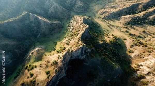 Obraz An aerial drone view captures rugged mountain slopes covered in sparse vegetation and dramatic shadows showcasing textured geological formations