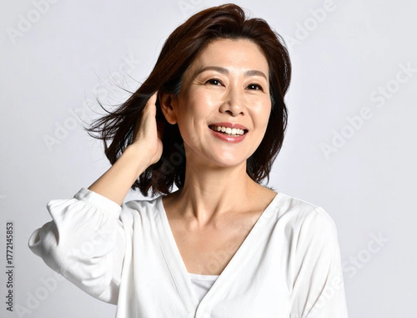 Obraz 笑顔で髪を触る中年女性