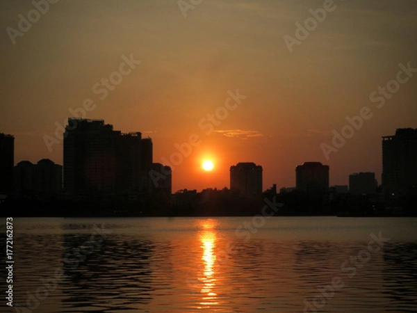 Fototapeta Golden Sun Over Quiet Lake: Minimal Skyline and Gentle Ripples on West Lake in Hanoi, Vietnam