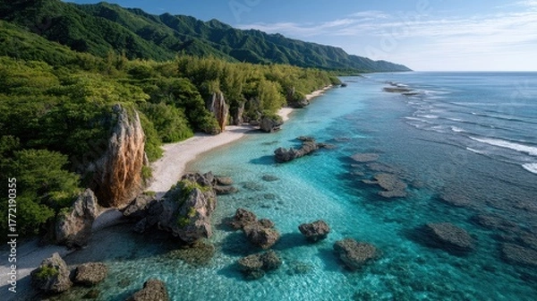 Fototapeta Drone Aerial View Of A Lush Green Island Coastline With Dramatic Jagged Rock Formations And Turquoise Crystal Clear Ocean Waters Under Bright Sunlight