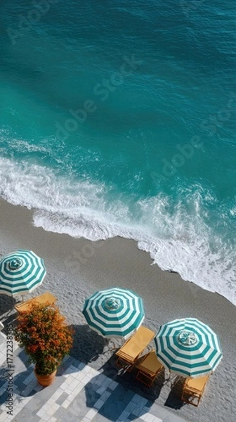 Obraz Top View Of A Serene Rocky Beach With Teal Ocean Waves And White Striped Umbrellas On A Sunny Day