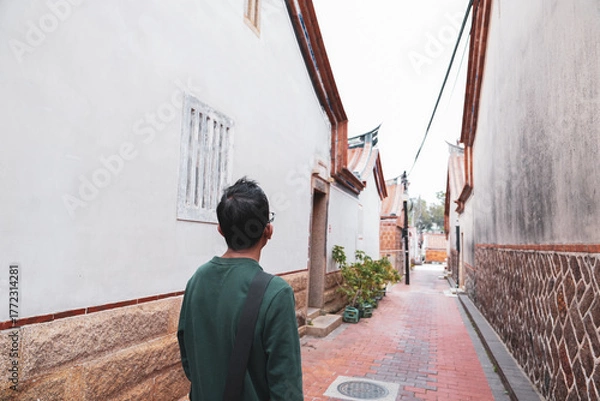 Fototapeta Tourist exploring Fujian-style houses in old village of Kinmen. Back view, selective focus.
