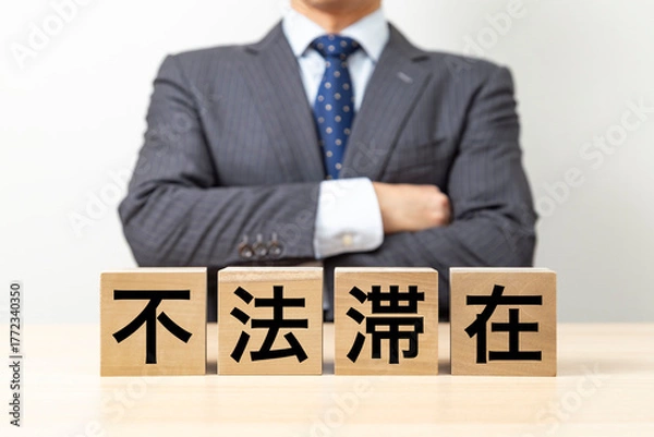 Obraz 「不法滞在」と書かれたブロックと腕組みをするビジネスマン