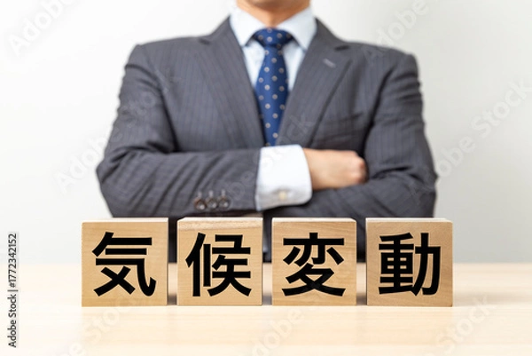 Fototapeta 「気候変動」と書かれたブロックと腕組みをするビジネスマン