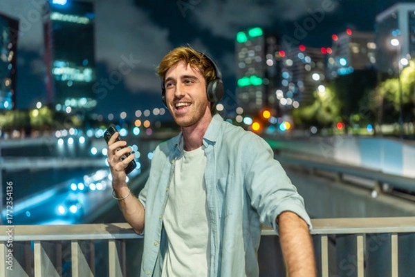 Obraz Young man enjoying music at night city