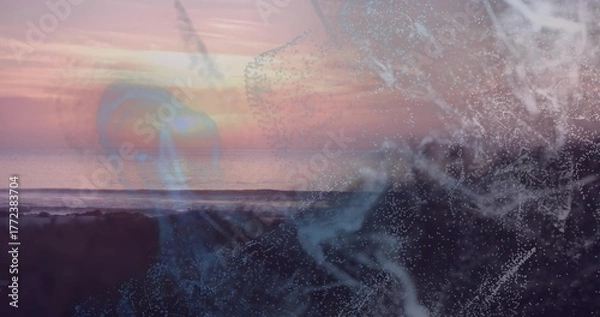 Obraz Glowing abstract digital particle swirl drifting across rocky shoreline, with ocean horizon overlay