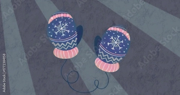 Fototapeta Displaying blue mittens with snowflakes and pink cuffs connecting by navy cord on lit gray surface
