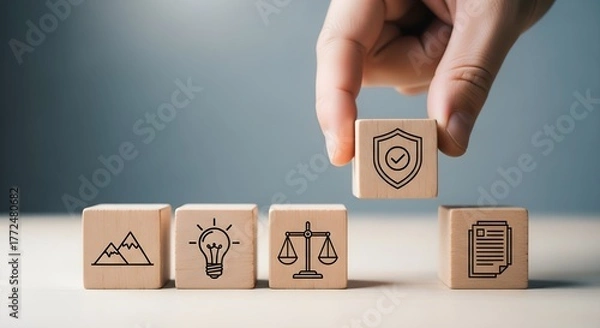 Fototapeta Hand places wooden block with shield icon on top of other blocks representing concepts