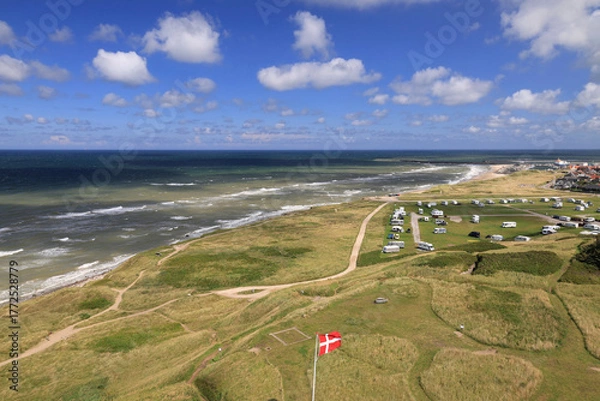 Fototapeta Landscape photo with a view of the green hills and North Sea coast with the Danish flag in the foreground near Hirtshals in Denmark 