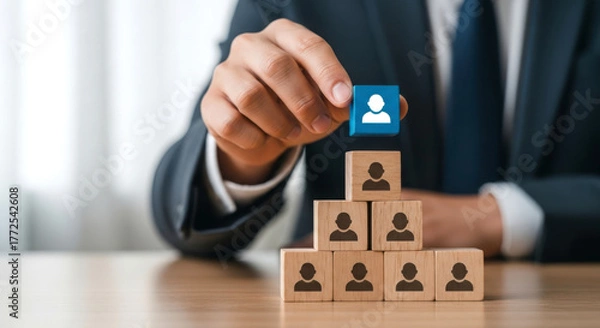 Fototapeta Businessman building a team by placing a new person icon on top of blocks