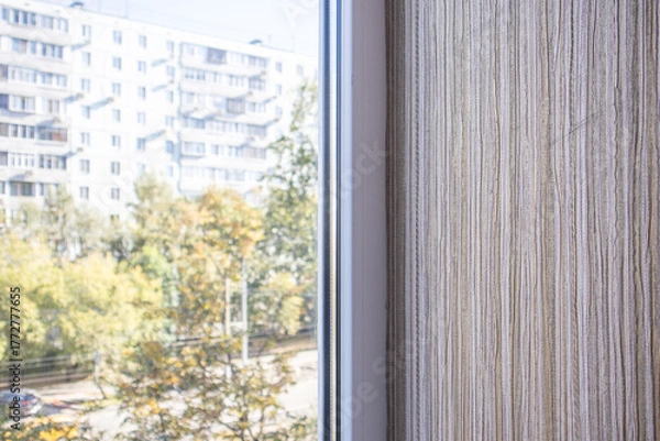 Fototapeta Textured beige wall by window city view and trees soft daylight horizontal frame