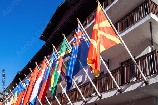 Obraz Multiple flags display at a building under a clear blue sky