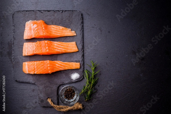 Fototapeta Raw salmon filet on dark slate background