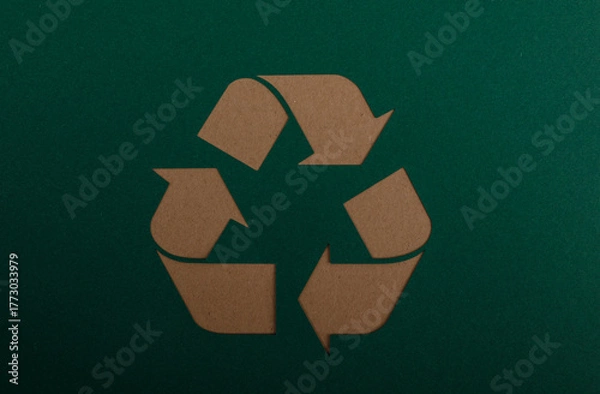 Fototapeta A close-up shot of a recycling symbol on a dark green background, representing environmental awareness, sustainability, and waste reduction. Ide