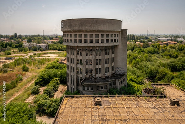 Obraz Abandoned distillery tower in Italy – circular industrial building with glass dome, steel beams, panoramic windows, decaying factory interior, urban exploration, post-industrial architecture