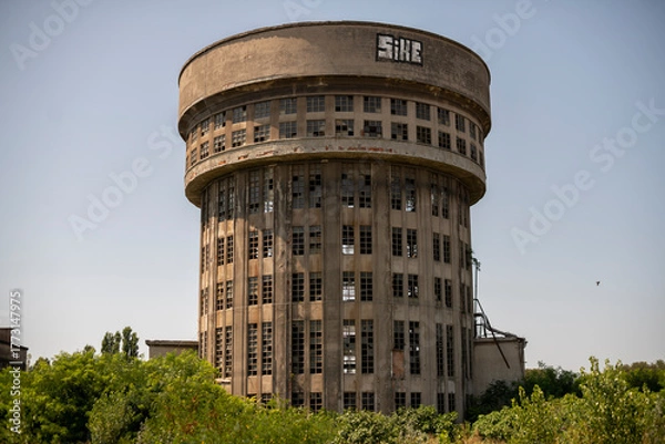 Fototapeta Abandoned distillery tower in Italy – circular industrial building with glass dome, steel beams, panoramic windows, decaying factory interior, urban exploration, post-industrial architecture