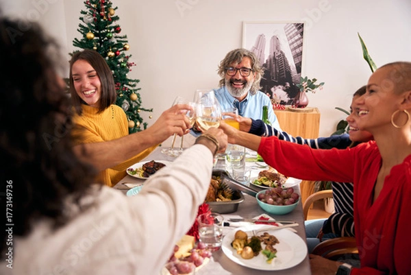 Fototapeta Diverse generations of happy Caucasian people celebrating domestic life toast with glasses white wine at home. Smiling family meeting enjoying Christmas meal together at festive holiday table indoors
