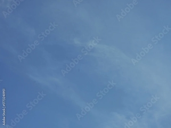 Fototapeta A bluish sky background with a pattern of soft white clouds. Full frame of a soft cloudy sky.