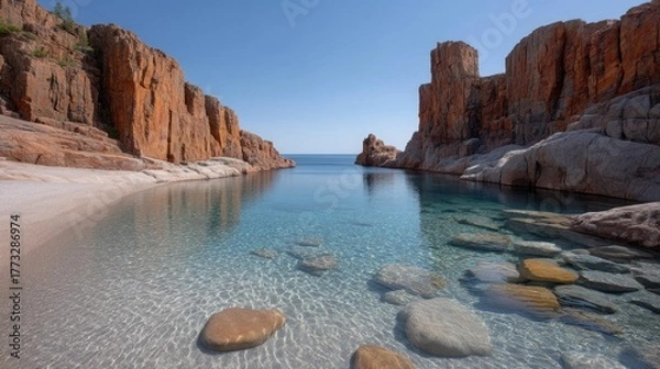 Fototapeta Wide Angle Rocky Coastal Mountain Landscape With Clear Turquoise Water And Sunlight Reflections Under A Bright Blue Sky