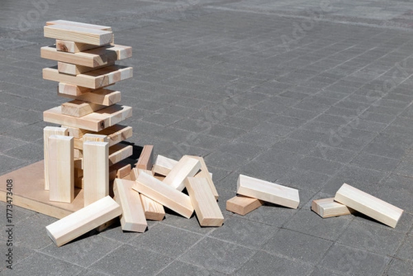 Fototapeta Large wooden blocks against a gray tile background. Wooden block tower. Business concept.