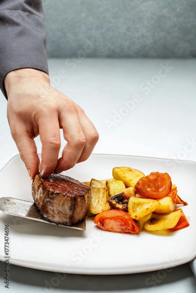 Obraz Chef plating a perfectly cooked steak with roasted vegetables