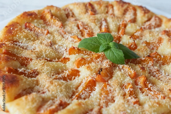 Fototapeta A delicious apricot pie on a white wooden table, close-up. A delicious dessert.
