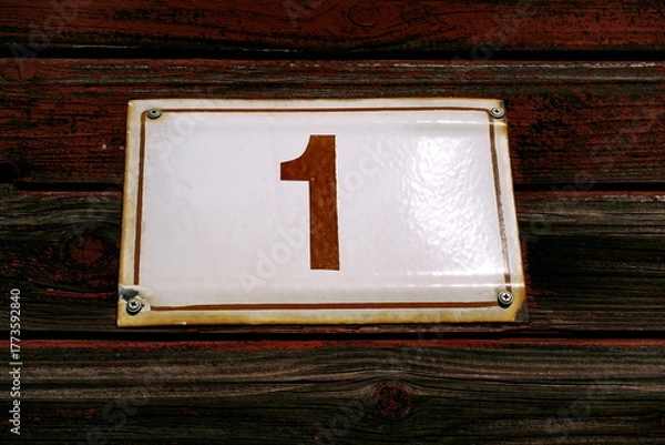 Fototapeta Numéro 1. Plaque de numéro de rue sur façade en bois peint en rouge.