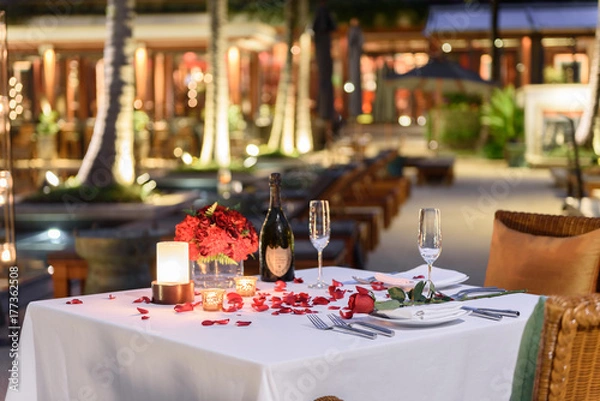 Fototapeta Special romantic candle light dinner table set up by the pool for couple with a bottle of champaign