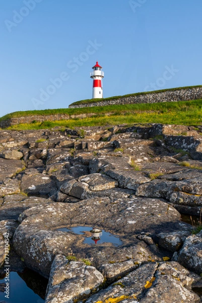 Fototapeta vertical view of the Torshavn Lighthouse at the Skansin Fortress on the Faeroe Islands at sunrise