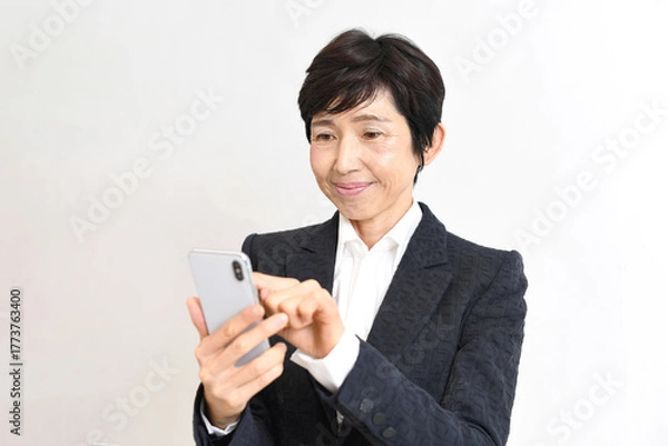 Obraz スーツ姿のアジア人シニア女性がスマホ操作