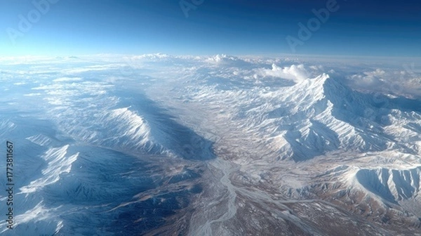 Fototapeta Aerial View of Snow Capped Mountain Range Under a Clear Blue Sky With Sunlight Illuminating Peaks and Valleys