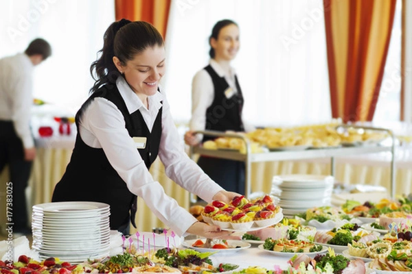 Fototapeta Restauracja kelnerka serwująca stół z jedzeniem