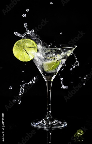 Fototapeta Martini splash in a cocktail glass with a slice of lime on a side