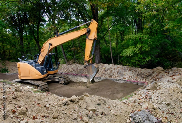 Fototapeta Backhoe leveling sand that has been laid as the bottom level of a septic system drain field
