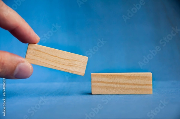 Fototapeta Hand placing wooden block on tower symbolizing strategy, planning, and balance with customizable space for text or ideas.