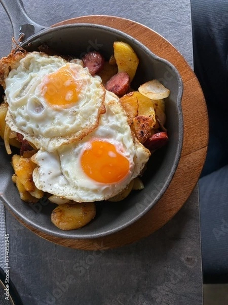 Obraz two fried eggs with fried potatoes in cast iron pan