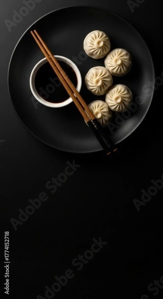 Fototapeta Steamed Dumplings with Soy Sauce on Black Plate with Chopsticks in Modern Minimalist Setting
