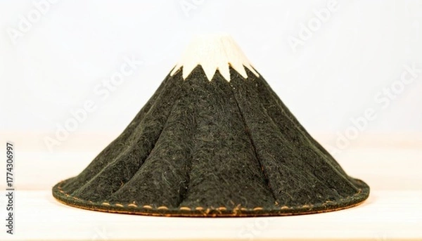Fototapeta A dark, cone-shaped hat with a white top, resembling a stylized mountain.