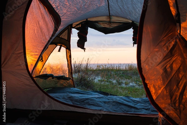 Fototapeta Scenic view from inside an open tent overlooking the Baltic Sea coast at sunrise during a wild camping trip in Estonia.